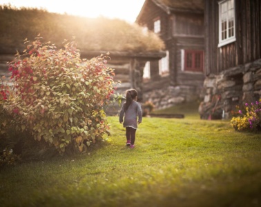 Urlaub auf dem Bauernhof in Norwegen:Mädchen spaziert durch einen Garten
