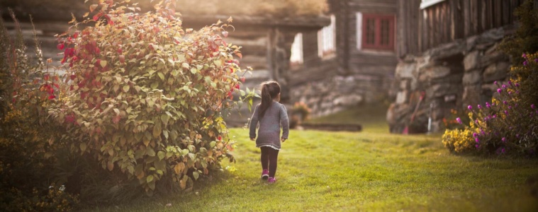 Urlaub auf dem Bauernhof in Norwegen:Mädchen spaziert durch einen Garten