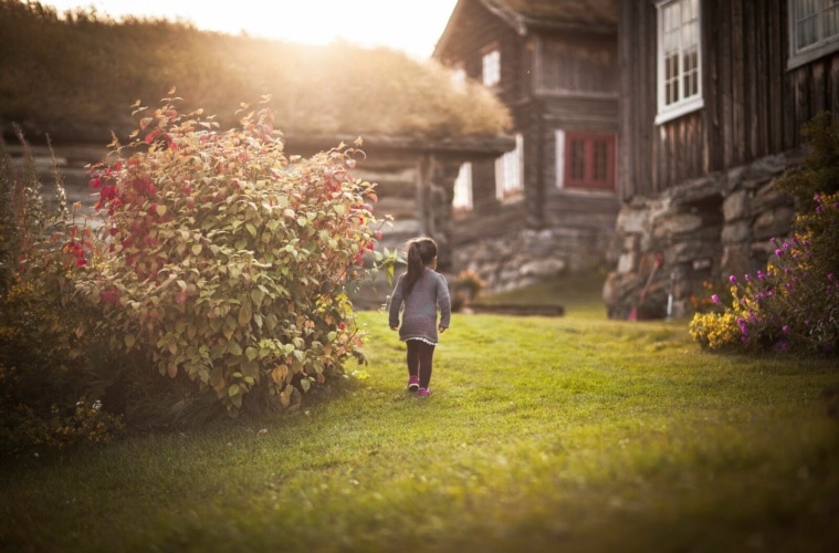 Urlaub auf dem Bauernhof in Norwegen:Mädchen spaziert durch einen Garten