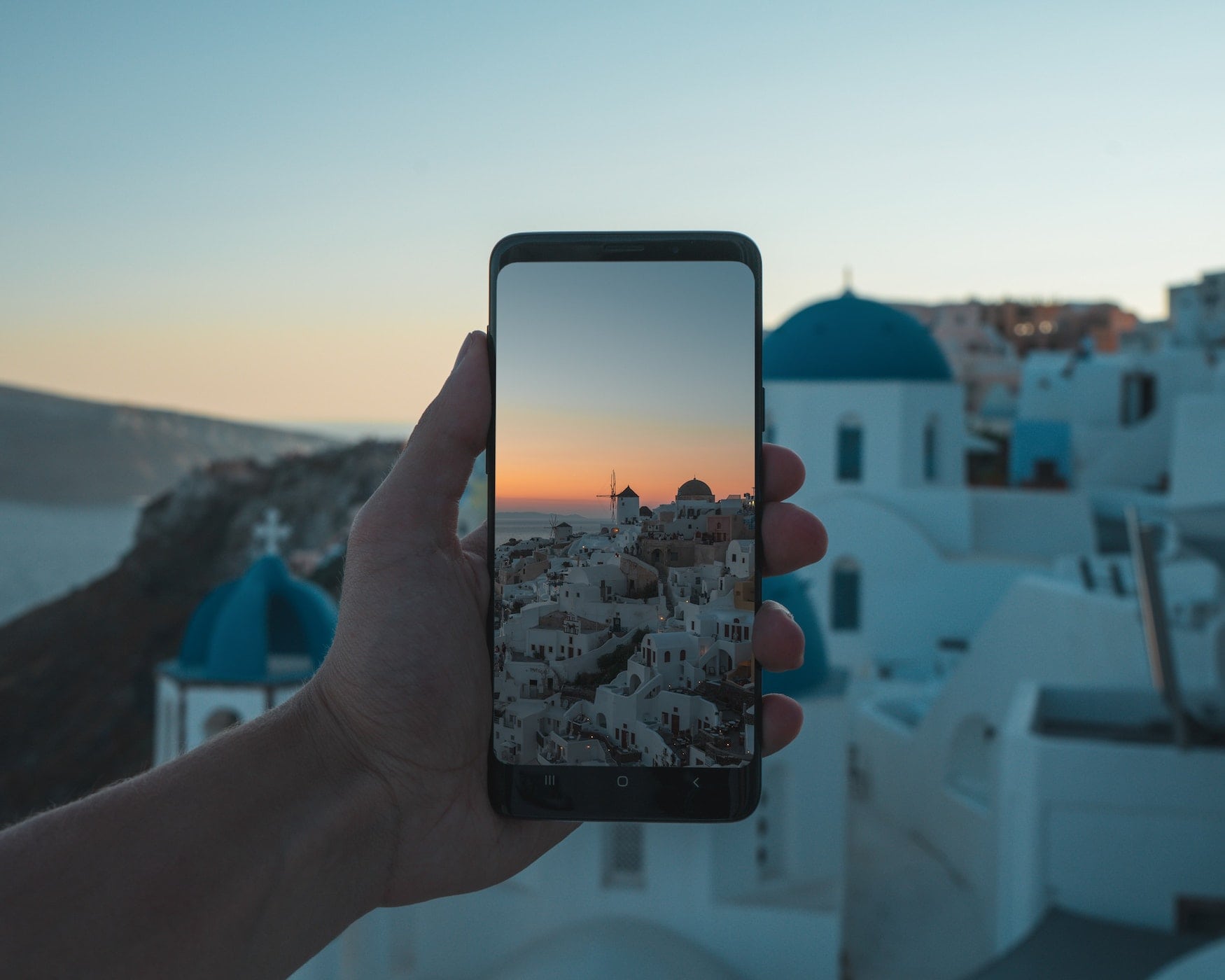 Mann nimmt ein Foto beim Sonnenuntergang auf Santorin auf mit Smartphone