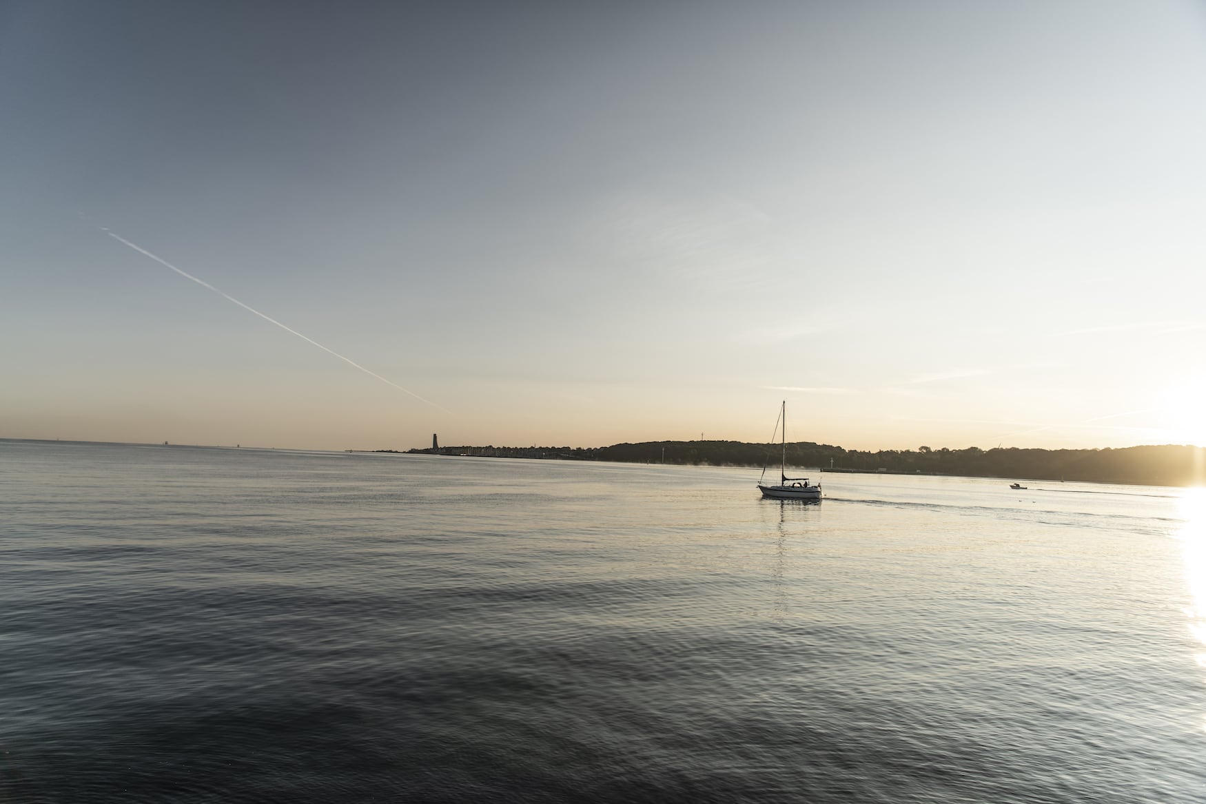 Ein Segelboot auf der Kieler Förde. Im Hintergrund befindet sich das Marine-Ehrenmal Laboe