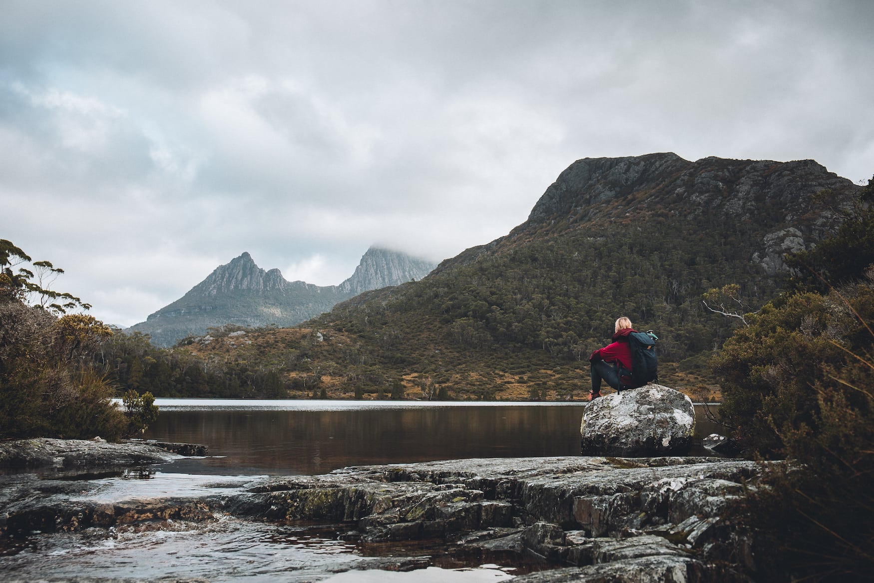 A female parker sits by Lake Lille in Cradle Mountain Lake St Clair National Park