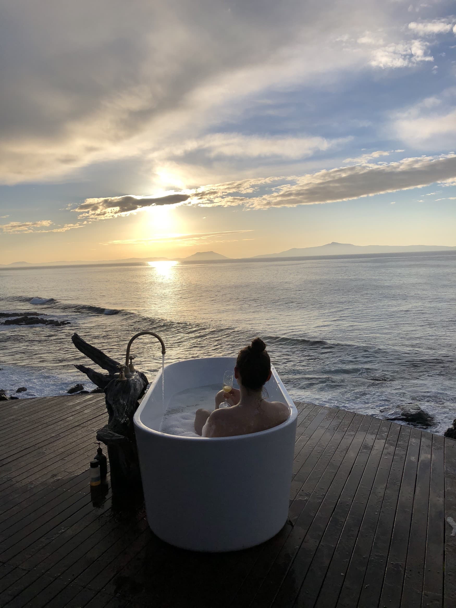 Woman lying in outdoor bathtub at Thalia Haven in Tasmania