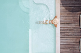 Frau mit Strohhut entspannt in einem Pool einer Traumvilla
