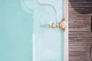 Frau mit Strohhut entspannt in einem Pool einer Traumvilla