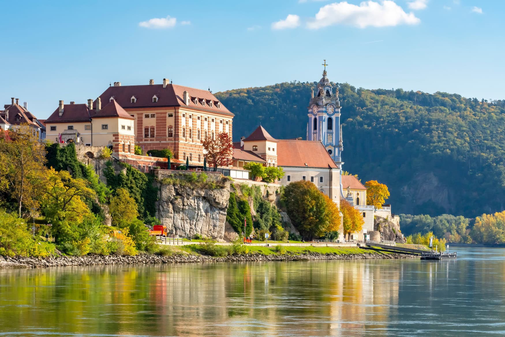 Blick vom Fluss auf den Ort Dürnstein, prominent der blaue Turm der Stiftskirche.