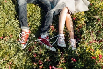 Pärchen mit Converse liegt im Gras