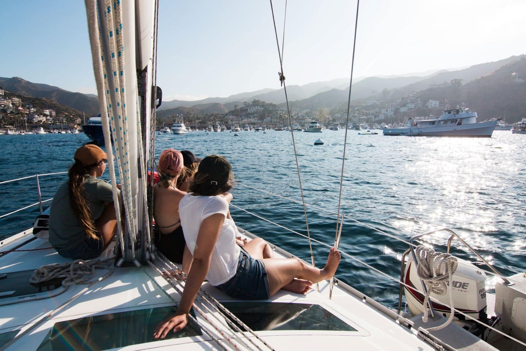 Vier Frauen sitzen auf Segelyacht und blicken auf den Hafen 
