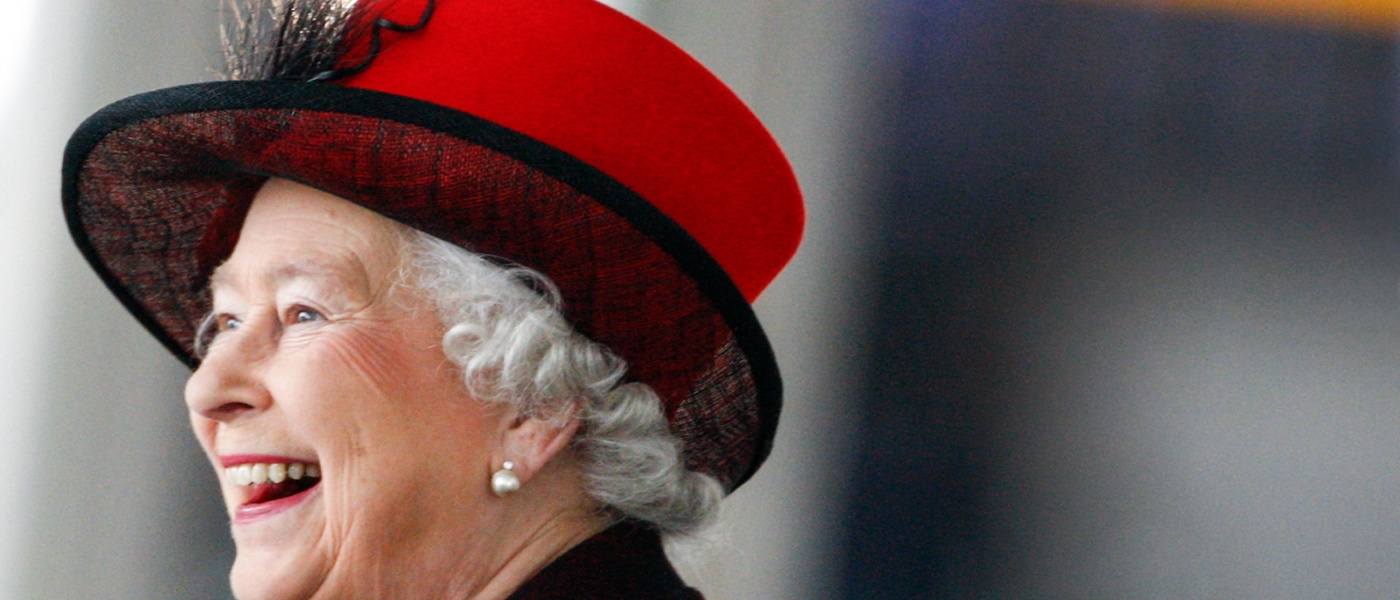 Queen Elizabeth II. lächelt und trägt einen roten Hut
