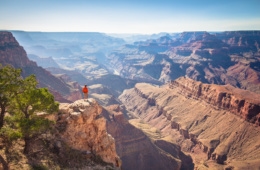 Wanderer in roter Jacke steht auf Felsen im Grand Canyon National Park