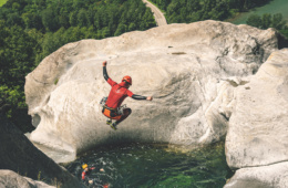 Mann springt von einem Felsen in ein Wasserbecken.