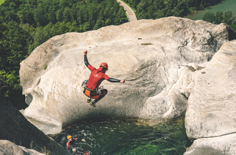 Mann springt von einem Felsen in ein Wasserbecken.