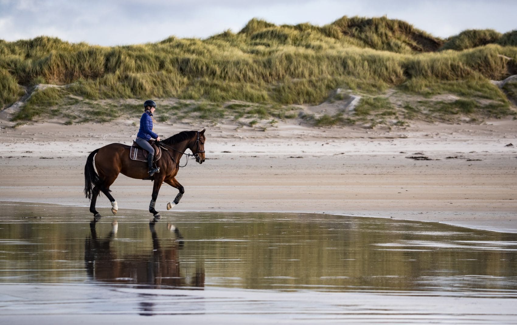 Reiterin auf Pferd an Strand in Irland 