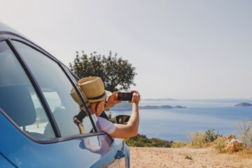 Türkei-Roadtrip: Ein Mann fotografiert aus einem Auto heraus das Meer.