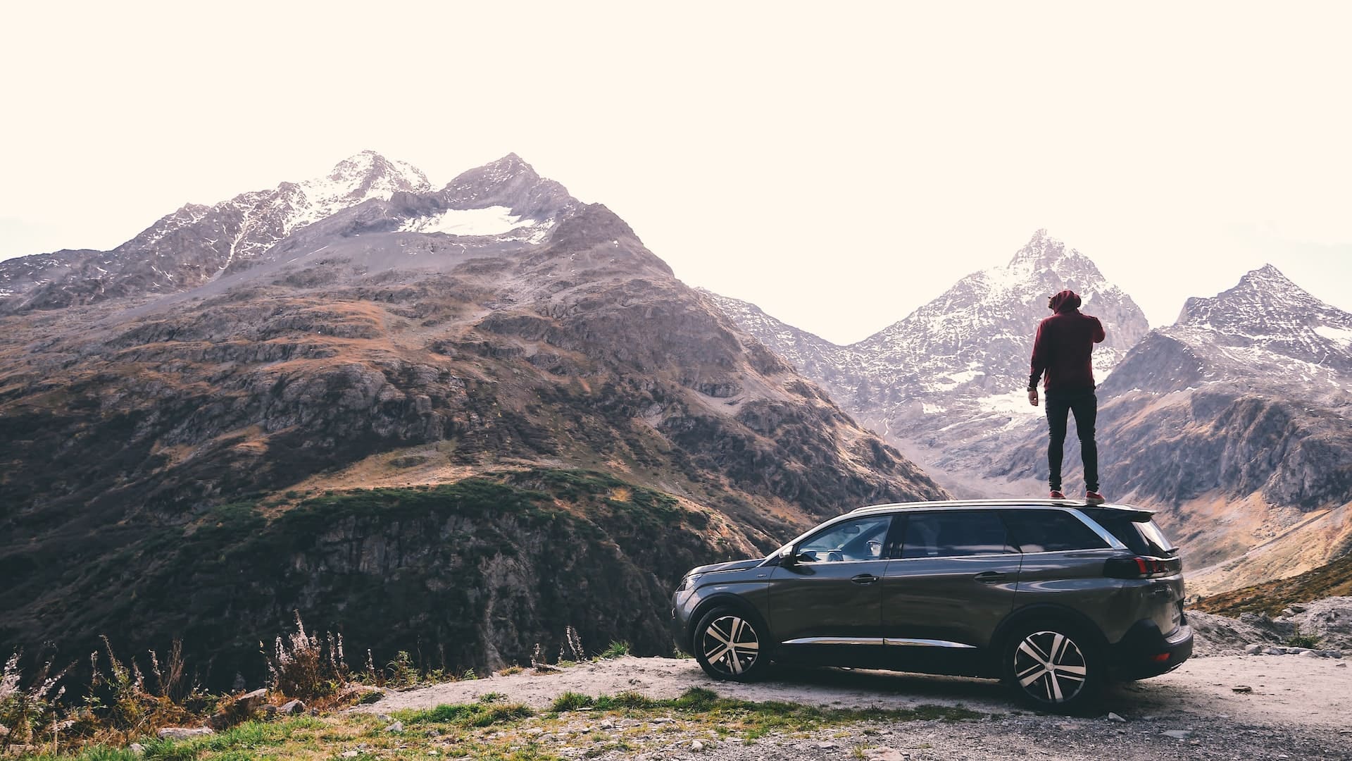 Mann steht auf Auto und genießt Ausblick auf Berge 