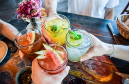 Vier Personen stoßen mit vier verschiedenen Cocktails an