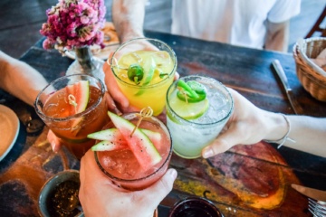 Vier Personen stoßen mit vier verschiedenen Cocktails an