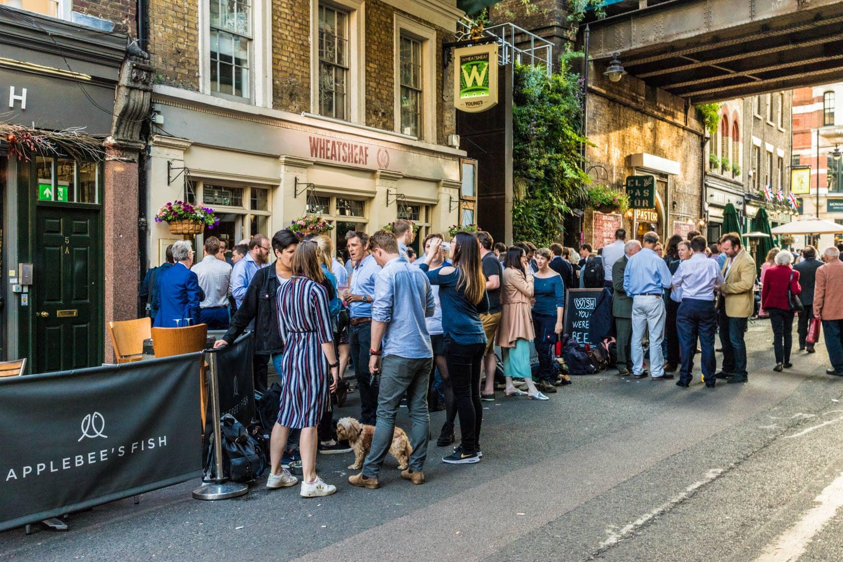 Besucher stehen draußen vor einem Pub in London und unterhalten sich 