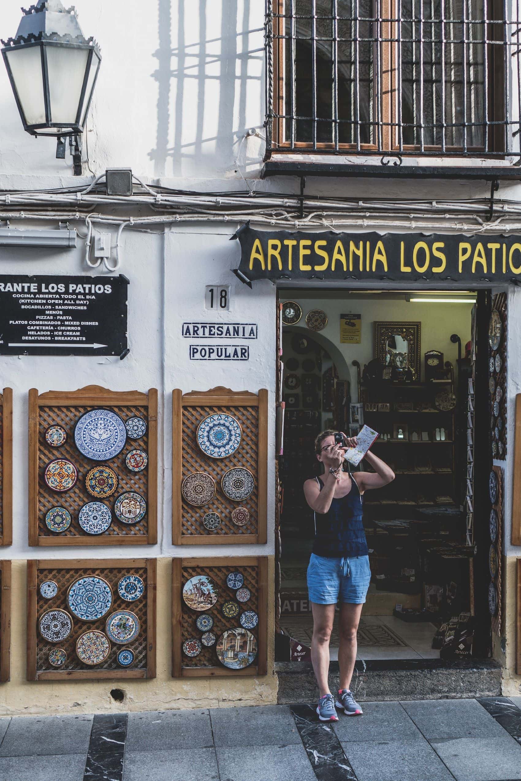 Frau macht Foto vor Kunsthandwerkshop in Cordoba 
