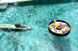 Frau schwimmt im Pool mit Floating Breakfast
