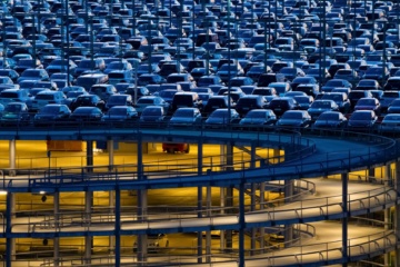 Garagengebäude mit Stahl- und Betonbau bei blauer Dämmerung und Hunderten von Autos auf Parkplätzen