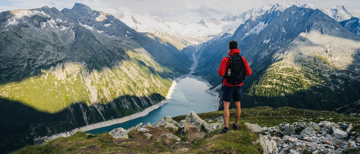 Mann wandert in den Alpen und genießt den Ausblick auf einen Bergsee