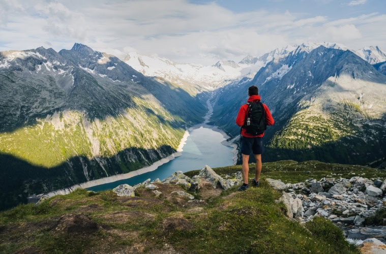Mann wandert in den Alpen und genießt den Ausblick auf einen Bergsee