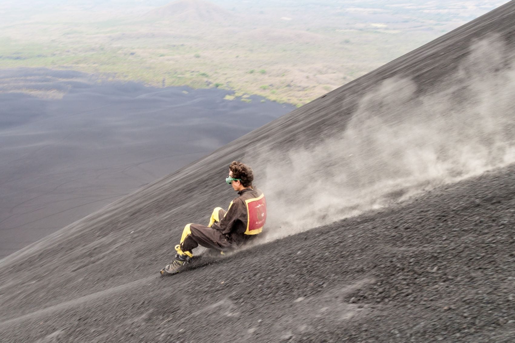 Mann fährt mit Schlitten Vulkan Cerro Negro runter 