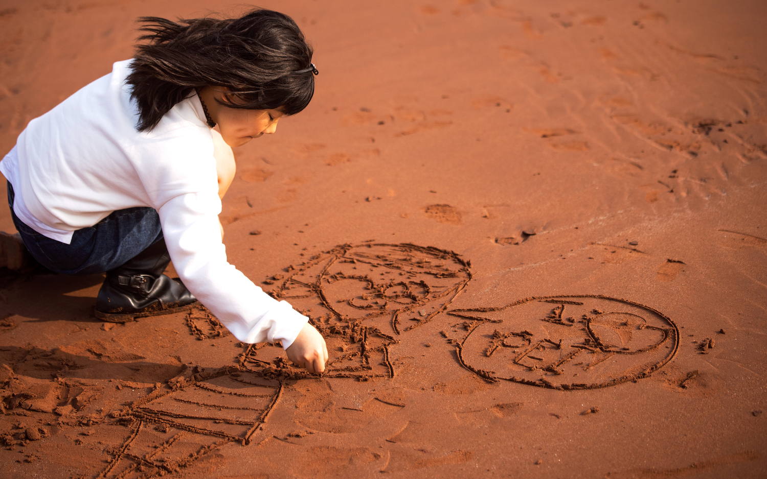 Mädchen malt etwas in den Sand von Prince Edward Island