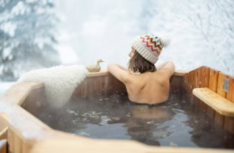 Frau sitzt mit Mütze im Winter im warmen Whirlpool