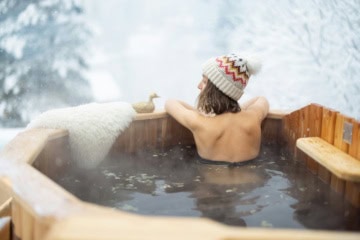Frau sitzt mit Mütze im Winter im warmen Whirlpool