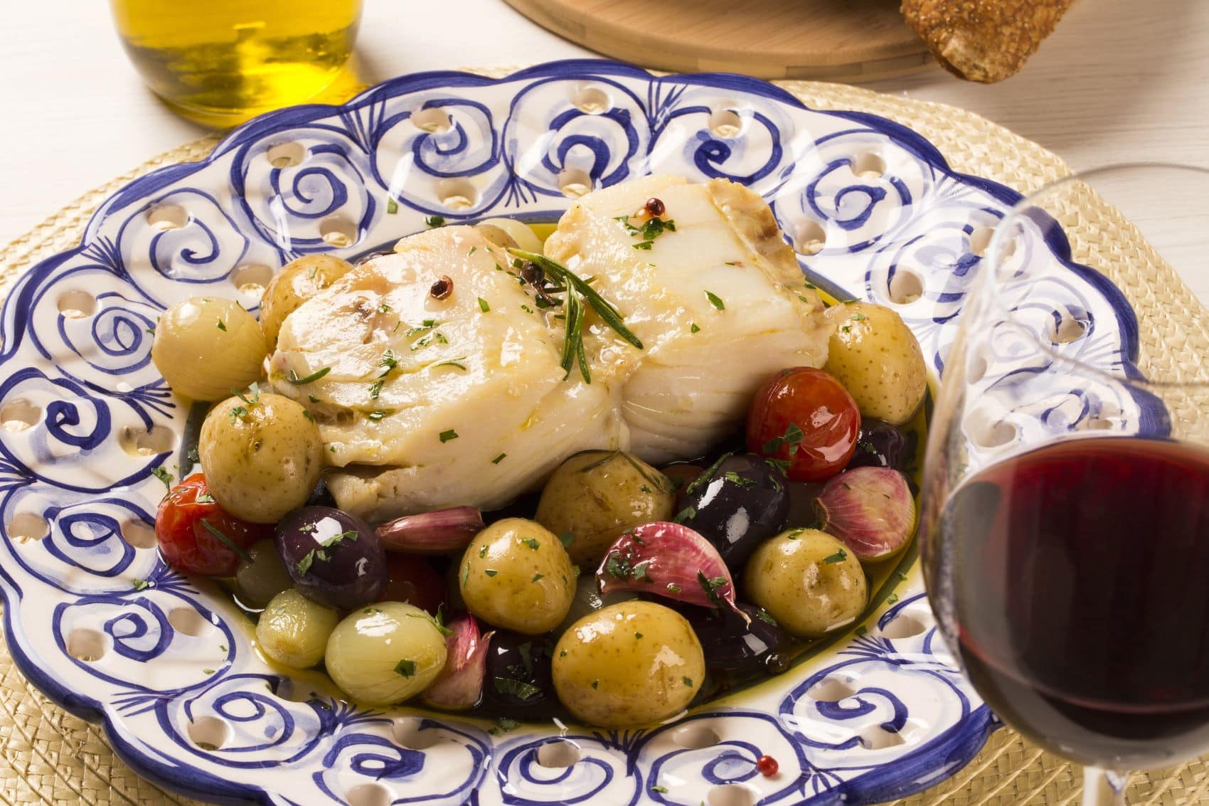 Bacalhau-Gericht auf Teller und Glas Rotwein 