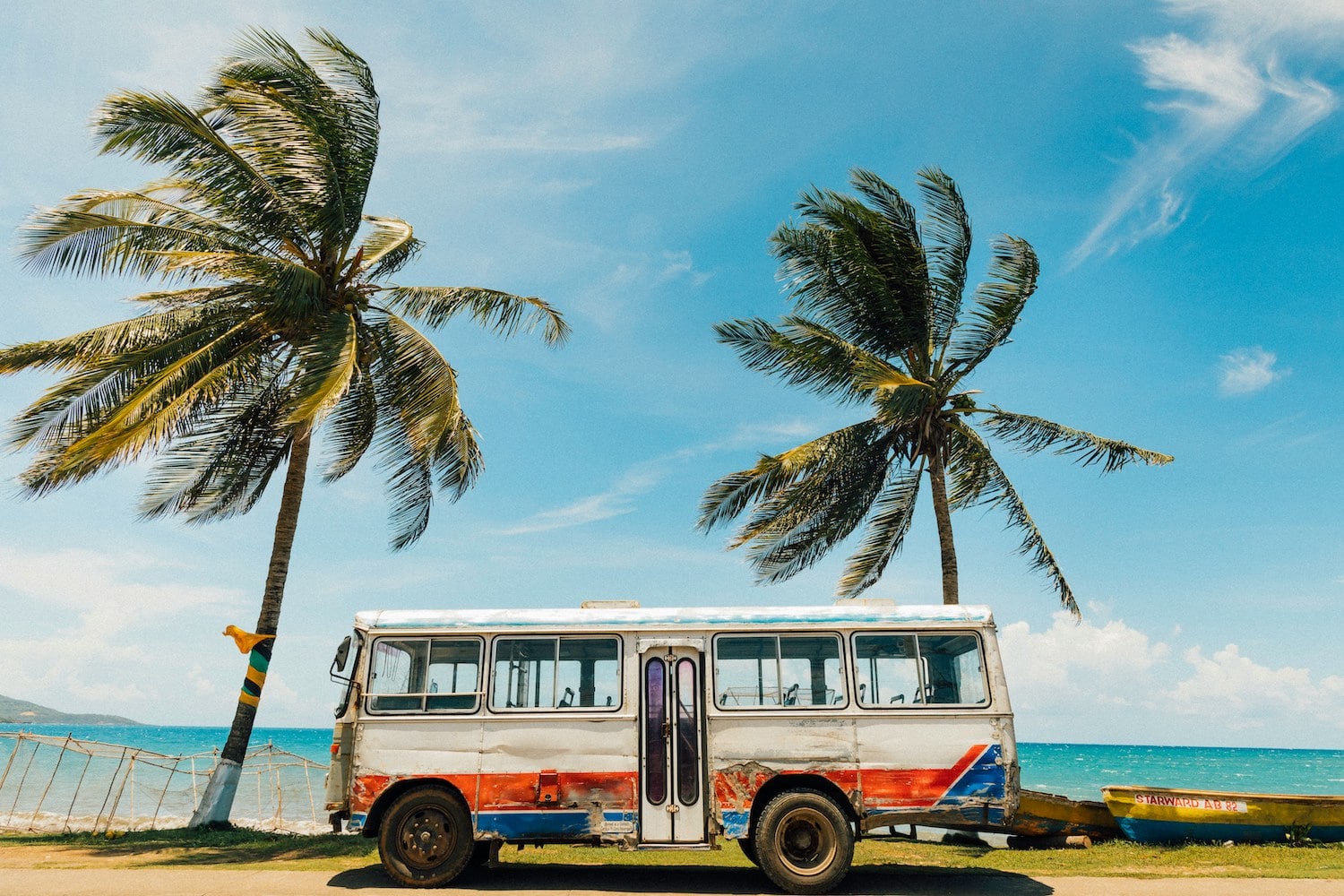 alter Bus vor Palmen und Meer in Jamaika in der Karibik