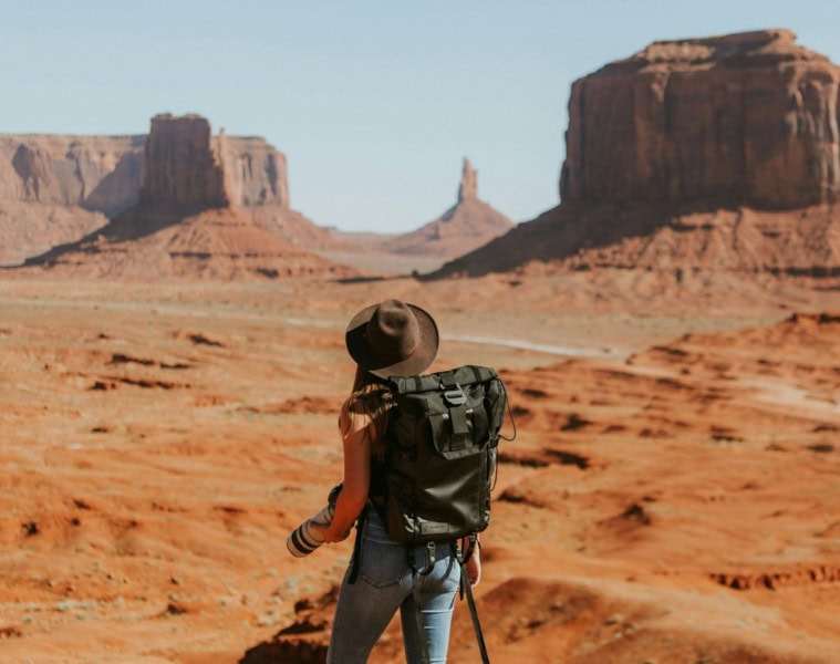 Frau mit Rucksack, Cowboyhut und Kamera im Oljato Monument Valley