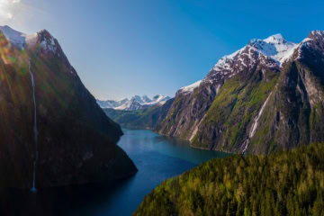 Zwischen zwei Gipfelketten in den Sunnmore-Bergen in Norwegen erstreckt sich im Licht der Sommersonne ein tiefblauer Fjord.