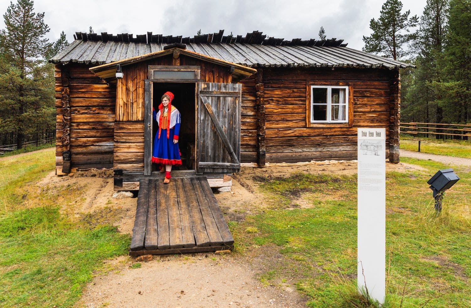 Eine Frau im Gewand der Samen steht vor dem Siida Freilichtmuseum in Lappland