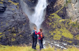 Zwei Personen stehen vor einem Wasserfall in Norwegen