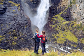 Zwei Personen stehen vor einem Wasserfall in Norwegen