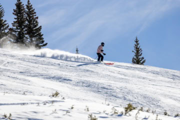 Ein Skifahrer fährt Ski an einem sonnigen Tag im Skigebiet