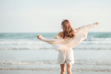 Frau mit Kopfhörern am Strand