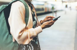 Frau mit Rucksack scrollt über Handy-Display