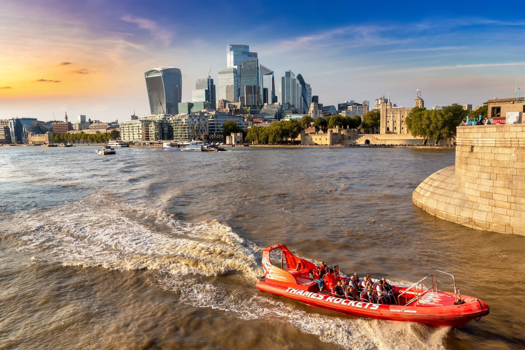 Vor dem Hintergrund der Londoner Skyline fährt ein rotes Schnellboot zügig über die Themse.
