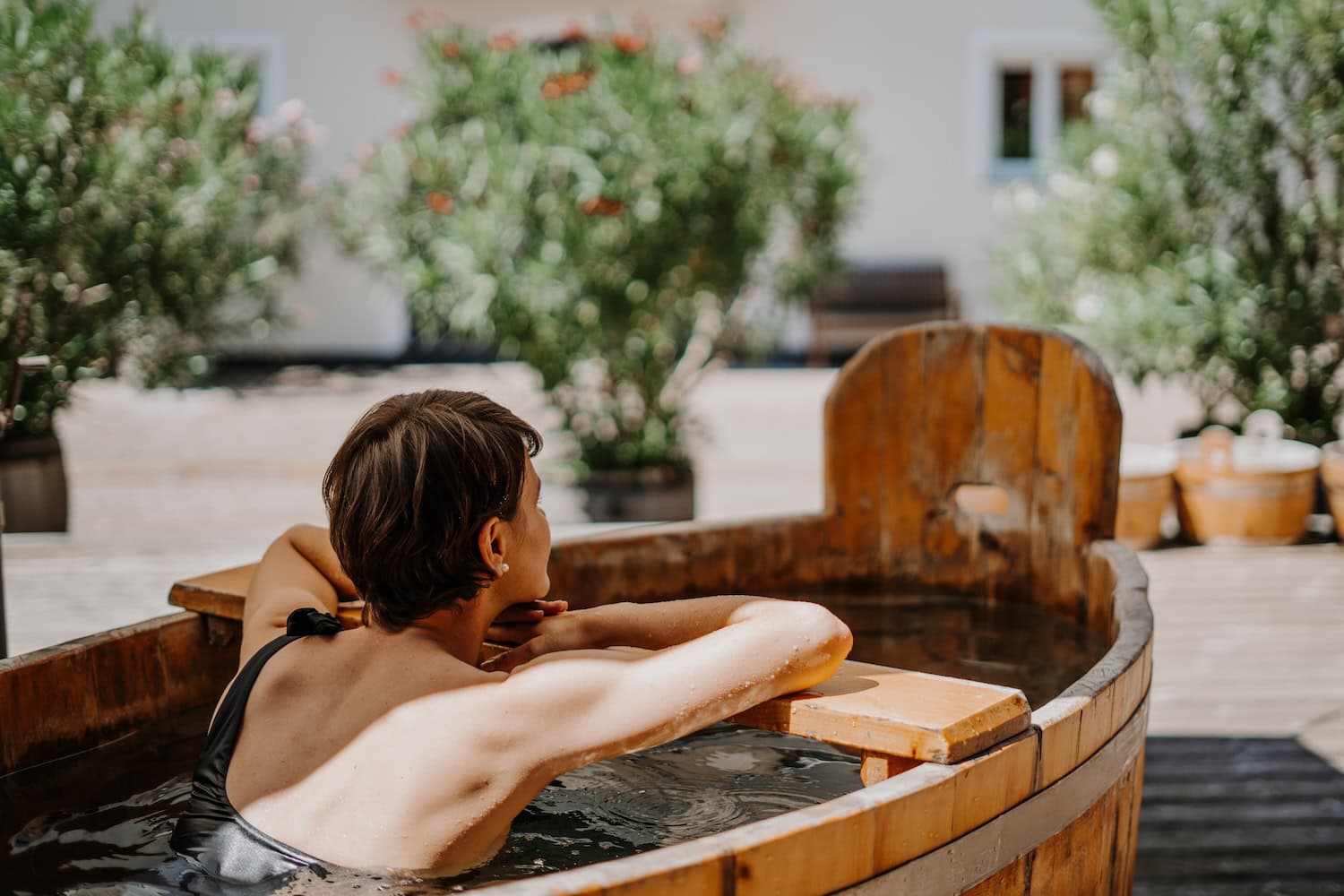 Eine Frau in einem Holzfass im Wellness-Bereich des Vinum Hotels Klosterhof.