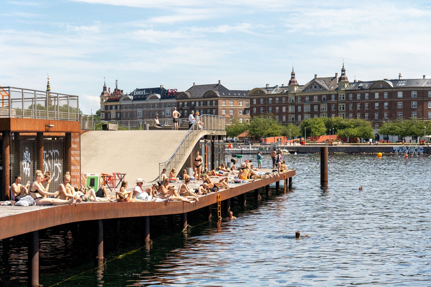 Besucher im Freibad Kalvebod Wave in Kopenhagen aalen sich in der Sonne. 