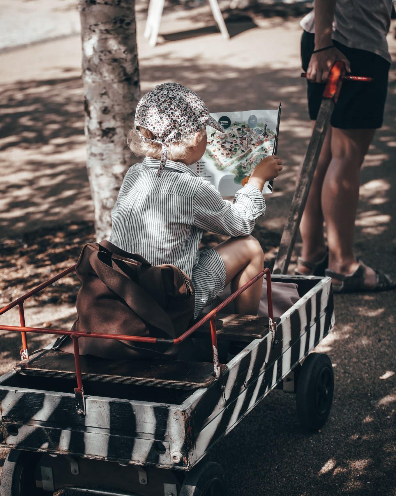 Mädchen mit Infoblatt in der Hand sitzt im Rollwagen im Kopenhagener Zoo.