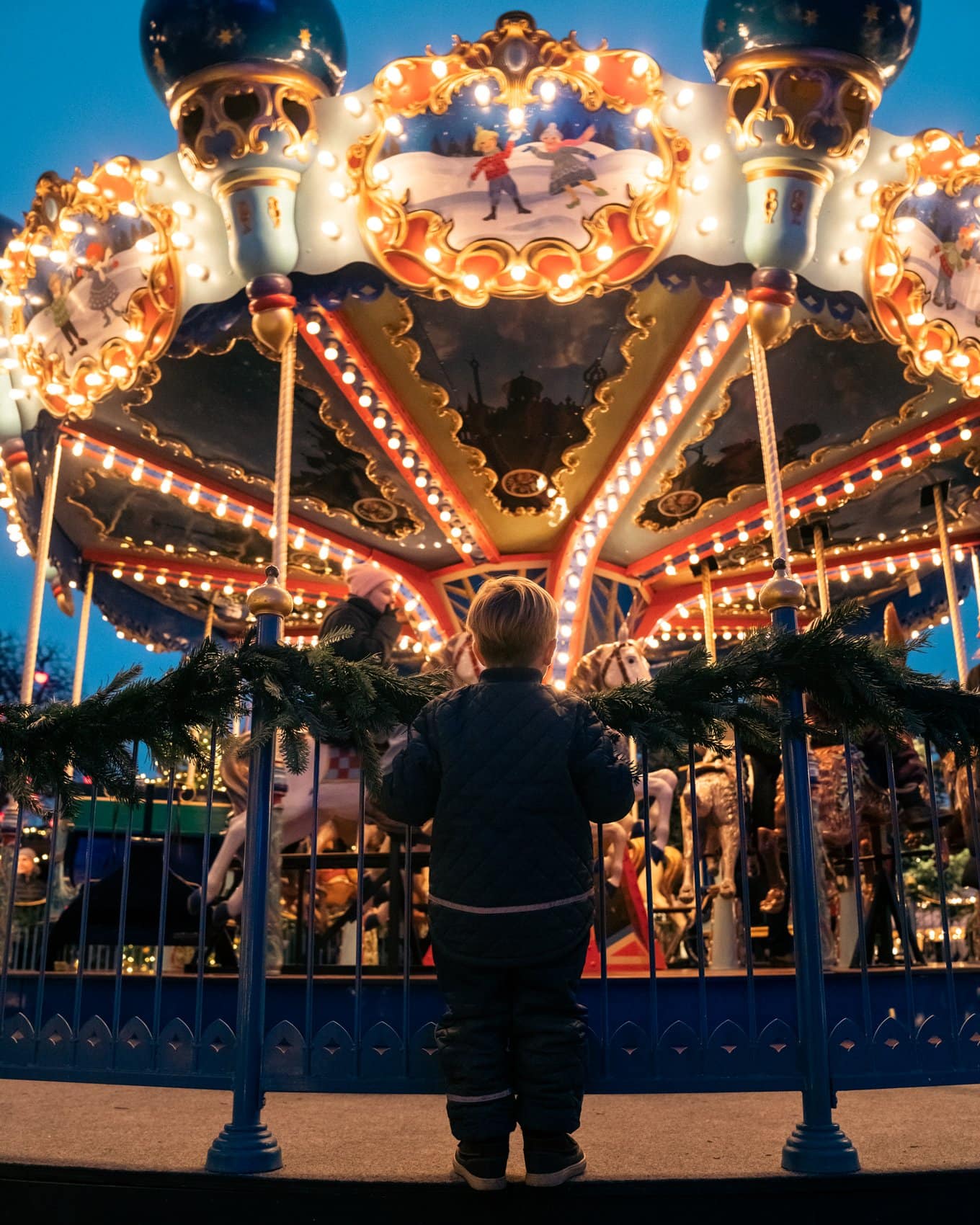 Kleines Kind steht vor Karussell im Tivoli-Park in Kopenhagen.