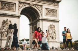 Touristen posieren vor dem Arc de Triomphe in Paris für ein Foto