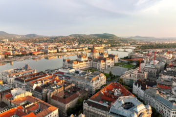 Luftaufnahme von Budapest an einem Sommertag, mit dem gut sichtbaren Parlament im Fokus.