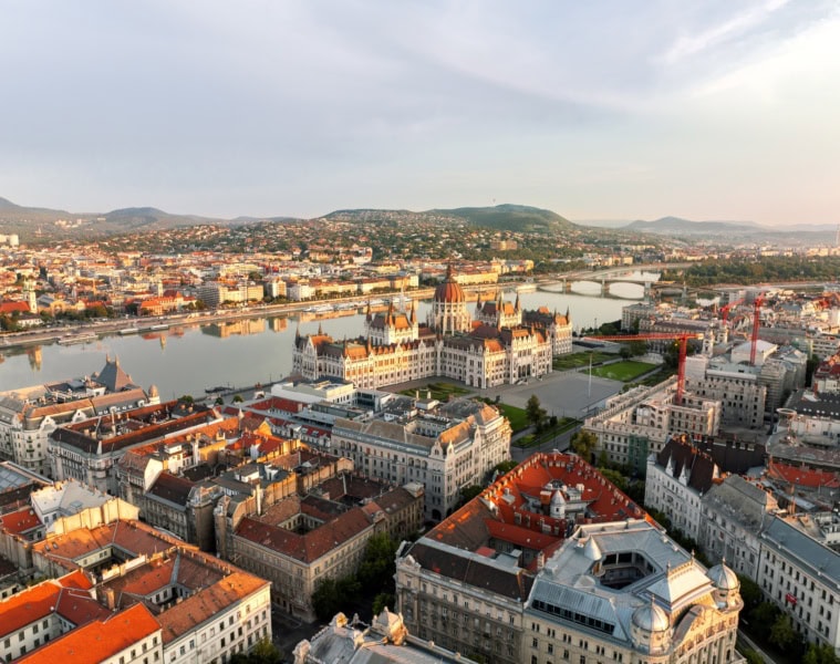 Luftaufnahme von Budapest an einem Sommertag, mit dem gut sichtbaren Parlament im Fokus.