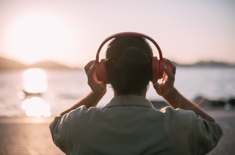 Ein Mann sitzt mit Kopfhörern am Meer.